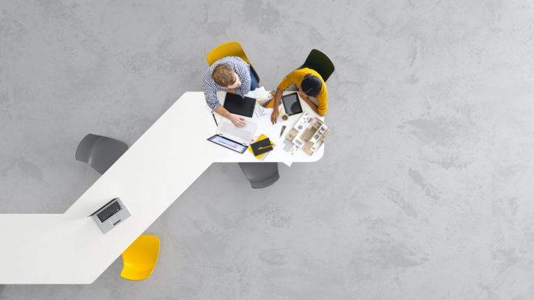 overhead of two employees working on their laptops