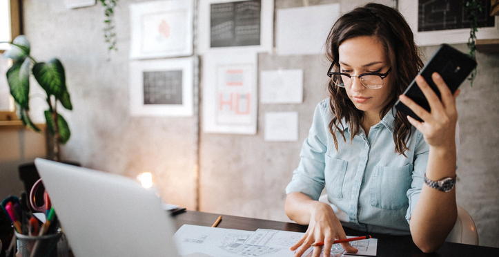 Women using phone and laptop while working