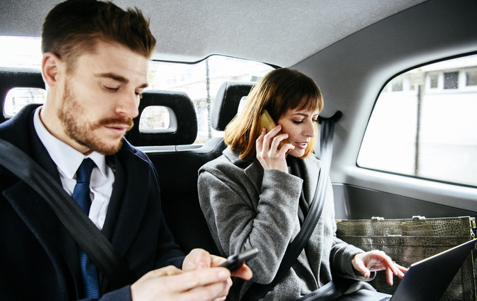 Man and women businesspeople on phones and laptop working wirelessly on the move